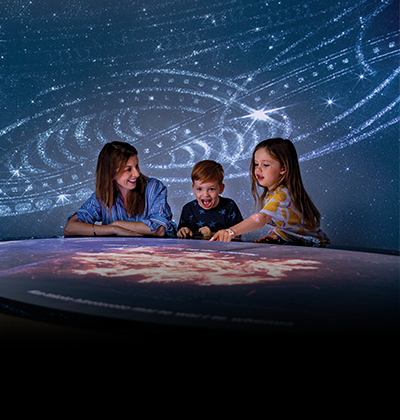 Mum and two kids using a digital interactive screen in a Museum gallery