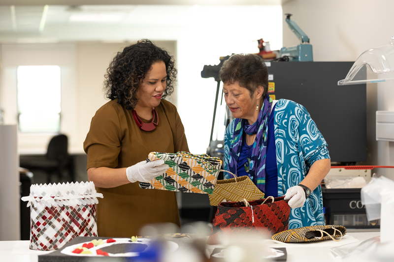 Museum workers inspecting kete, traditional Māori bags 